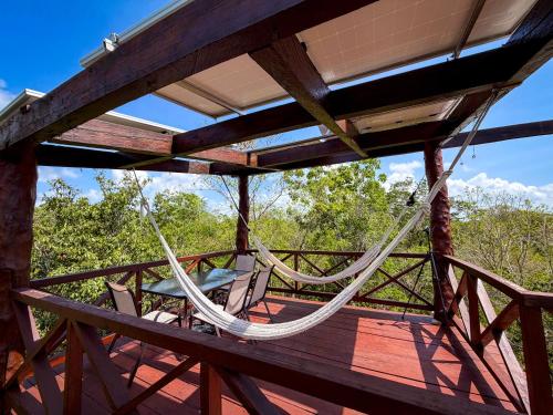 a hammock on a deck with a table and chairs at Treehouse Tulum H2Ojos in Tulum