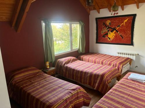a room with three beds and a window at LA CASONA in Villa General Belgrano