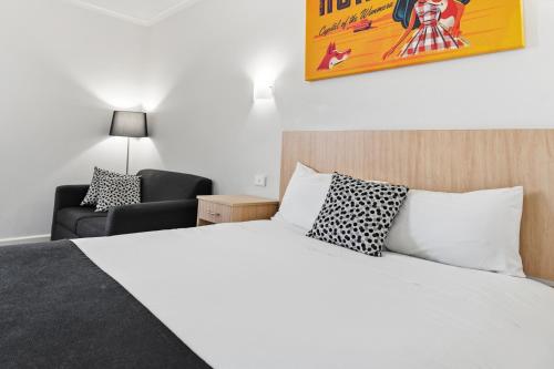 a bedroom with a white bed and a chair at The Capital Horsham in Horsham