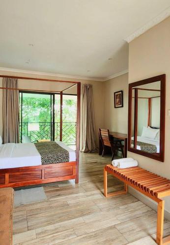 a bedroom with a bed and a mirror and a bench at Chinyonga Guesthouse in Limbe