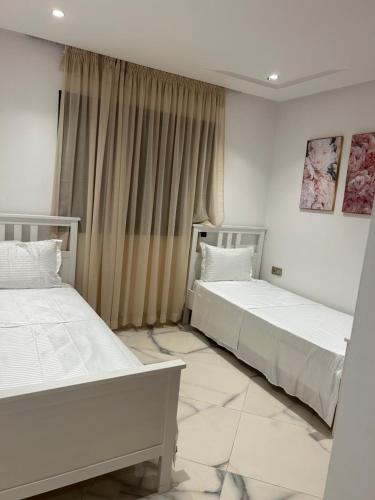 two beds in a room with white walls at belle appartement à centre Kénitra in Kenitra