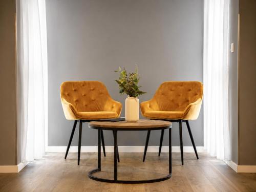 two chairs and a table with a vase on it at THE ROOMS - Hotel & House in Frankfurt
