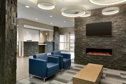 a lobby with blue chairs and a fireplace at Days Inn & Suites by Wyndham Warman in Warman