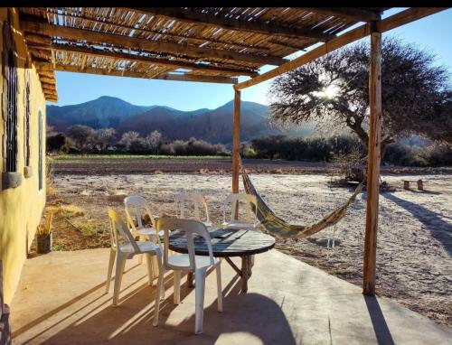 a table and chairs on a porch with a hammock at Cabañas Rurales HLS in Senador Pérez