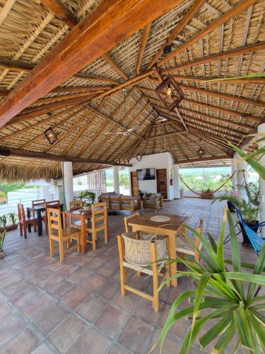 a patio with tables and chairs and a straw roof at Sicarú, La Punta - Puerto Escondido in Brisas de Zicatela