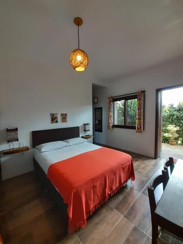 a bedroom with a large bed with a red blanket at Santa Monica Hospedaria in Praia do Rosa