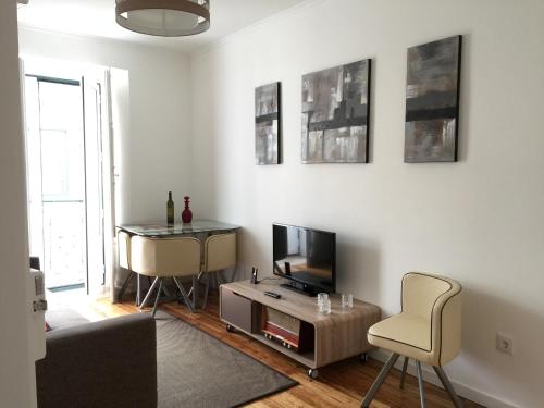 ein Wohnzimmer mit einem TV, einem Tisch und einem Stuhl in der Unterkunft Bairro Alto Studios & Flats by Lisbon Village Apartments in Lissabon