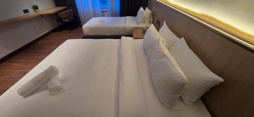 ein weißes Bett mit Kissen in einem Hotelzimmer in der Unterkunft Kingston Hotel 28 - Gocos Hotel Klang in Klang