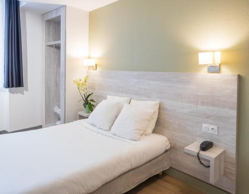 a bedroom with a white bed with two pillows at Campanile Grenoble Centre Gare in Grenoble