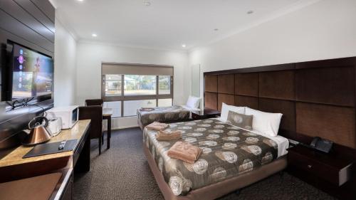 a bedroom with a bed and a desk and a television at Western Downs Motor Inn in Miles