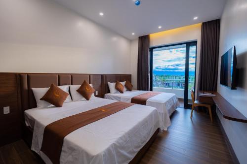 two beds in a hotel room with a large window at LunaB Hotel in Dong Hoi