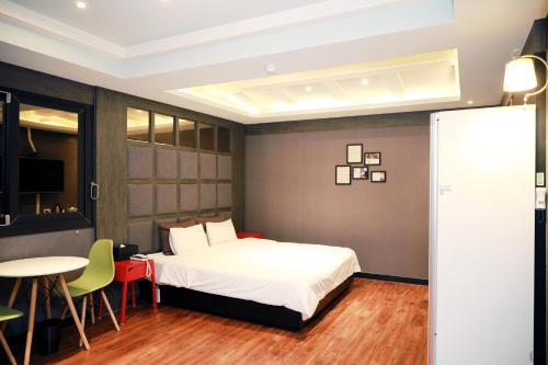 a bedroom with a bed and a table and chairs at 진해프렌치코드호텔 in Chinhae