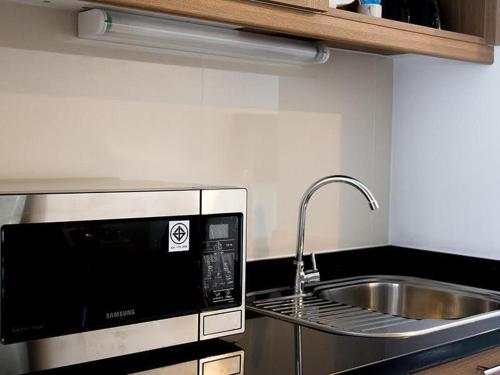 a kitchen with a sink and a microwave at We Grand Ever 9 in Nakhon Ratchasima