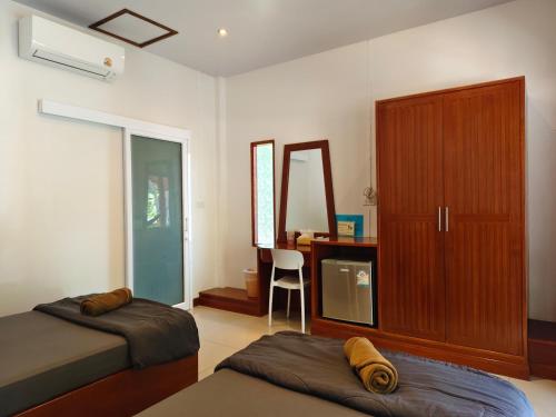 a bedroom with two beds and a cabinet and a mirror at Ban Tai Resort in Ban Tai