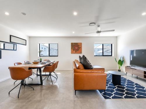 a living room with a table and chairs and a television at 3BR Top Floor Apartment with Parking, EV friendly & Views Brisbane South in Brisbane