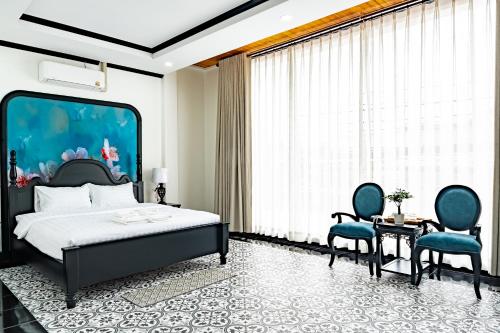 a bedroom with a bed and two blue chairs at La Resident Indochina Hotel in Vientiane