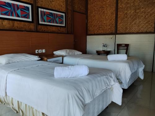 three beds in a hotel room with white sheets at Megamendung Hotel & Resort in Ciguntur