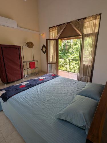 a large bed in a bedroom with a large window at Veridian Bloom in Ahungalla