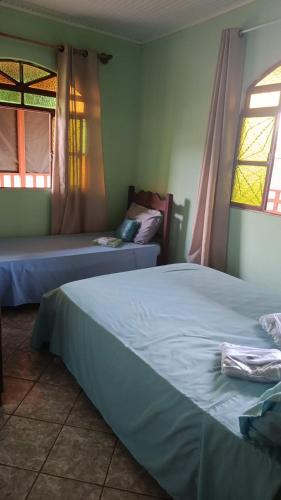 a bedroom with two beds and two windows at Pousada Bela Vista Santo Antônio do Manhuaçu in Caratinga