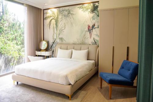 a bedroom with a bed and a blue chair at Samten Hills Villa Dalat in Xuan An
