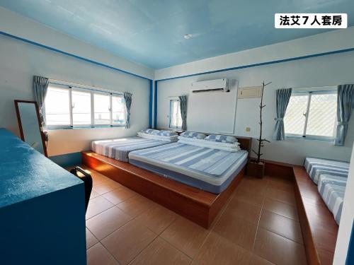 a room with three beds in it with windows at 法艾民宿 in Yeh-yin