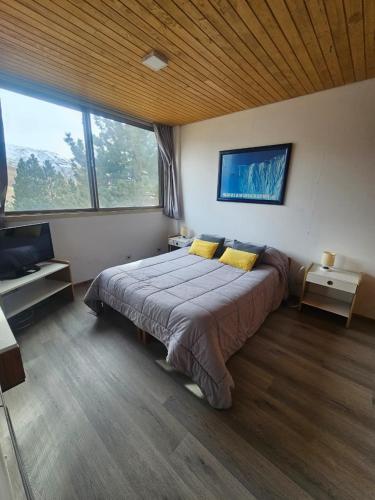 a bedroom with a large bed in a room with windows at Depto 7 personas - Edificio Cirrus in Las Lenas