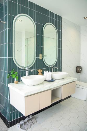a bathroom with two sinks and two mirrors at Samten Hills Villa Dalat in Xuan An