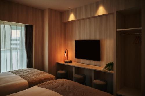 a hotel room with two beds and a flat screen tv at Moat Inside Hakata in Fukuoka