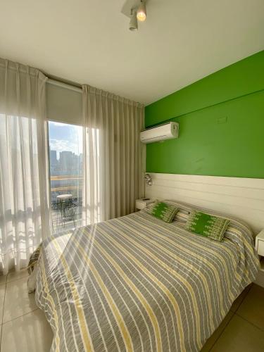 a bedroom with green walls and a bed with a window at 9 de Julio Park Suites in San Miguel de Tucumán