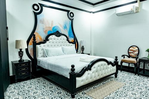 a bedroom with a black and white bed and a chair at La Resident Indochina Hotel in Vientiane