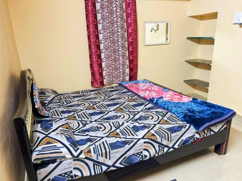 a small bed in a room with a bedspread on it at Siddhartha homevibes hampi in Hampi