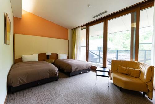 a hotel room with two beds and a couch at Jibuzaka Village Hotel in Achi