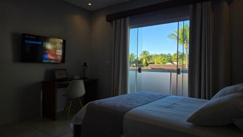 a bedroom with a bed and a window with a view at Pousada das Saíras in Paraty