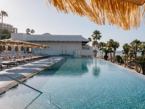 a swimming pool with chairs and a building at Zel Fuerteventura in Costa Calma