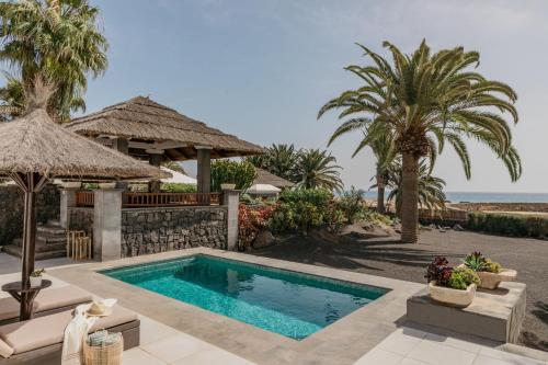 a villa with a swimming pool and palm trees at Paradisus Salinas Lanzarote - All Inclusive - Adults Only in Costa Teguise