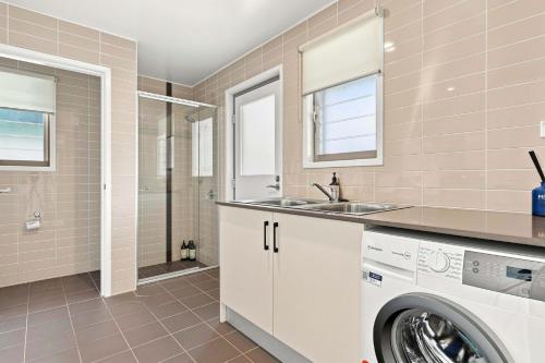 a bathroom with a washing machine and a sink at Coast Bliss on Currambene in Huskisson