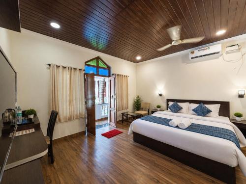 a bedroom with a bed and a desk and a window at Baga beach heritage resort in Calangute