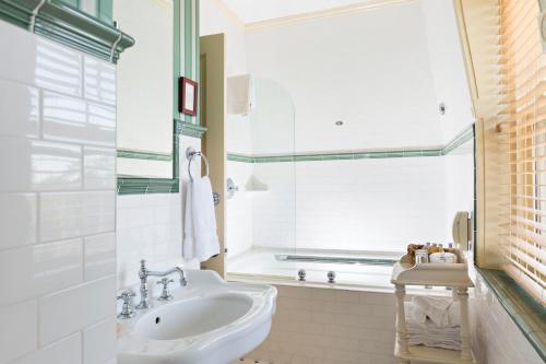 a white bathroom with a sink and a window at Brass Key Guesthouse Adults Only in Provincetown