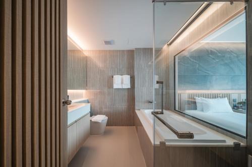 a bathroom with a bed and a sink and a mirror at Mandarin Eastville, Pattaya - SHA Extra Plus in North Pattaya