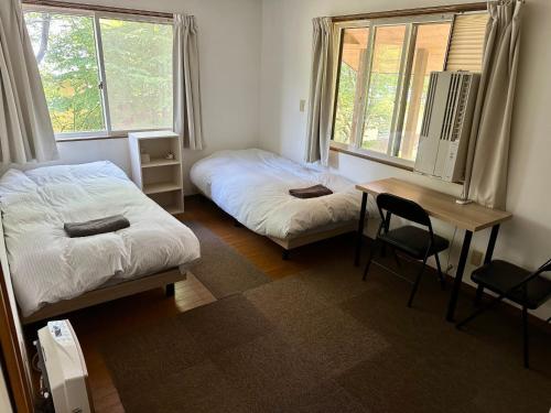 a bedroom with two beds and a desk and a table at KaKaJillJill in Hakuba