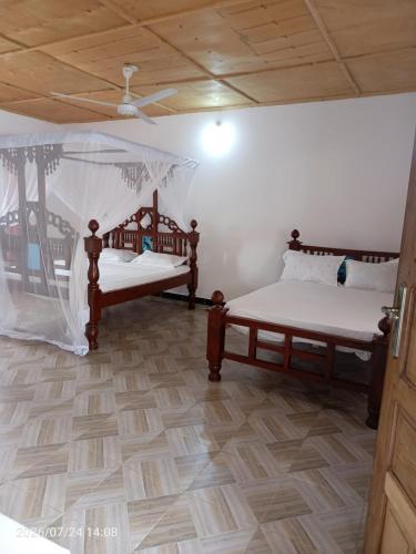 two beds in a room with a ceiling at Havilla Cecilia in Watamu