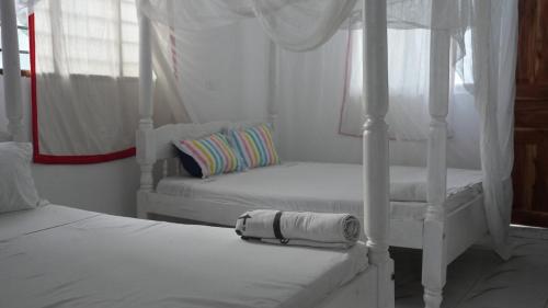 a white bedroom with two beds and a pillow at Havilla Cecilia in Watamu