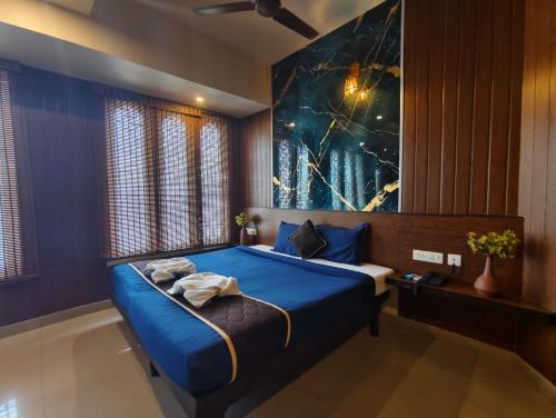 a bedroom with a blue bed with a painting on the wall at Arunik Inn in Pondicherry