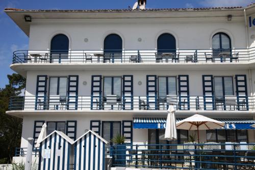 a white building with a balcony and an umbrella at Hotel Mercedes in Hossegor