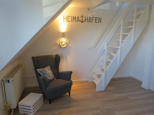a room with a chair and stairs with a sign that reads hermitehen at App "Ahoi" Familie Köhn in Schönberger Strand