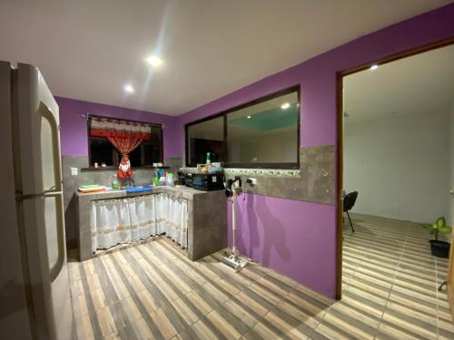 a kitchen with a purple wall and a counter at Casa Palo Verde in Bagaces