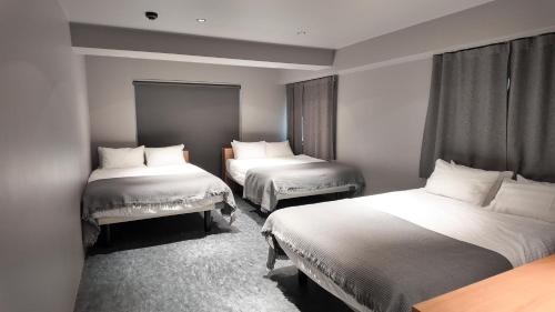a hotel room with two beds and two windows at 9STAY Kikukawa in Tokyo