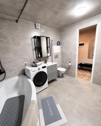 a bathroom with a washing machine and a bath tub at SMART flat - Ranna 49 in Sillamäe