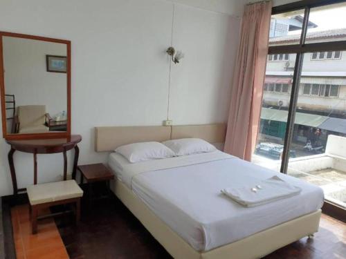 a bedroom with a bed with a mirror and a window at SA hotel in Trat