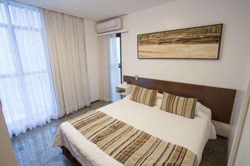 a hotel room with a bed and two windows at Hotel Brasil Tropical in Fortaleza
